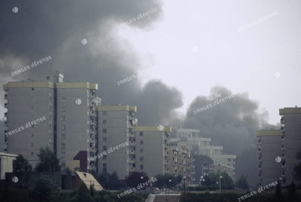 Un nuage de fumée s'élève derrière les immeubles dévastés par les tirs d'artillerie dans Sarajevo.