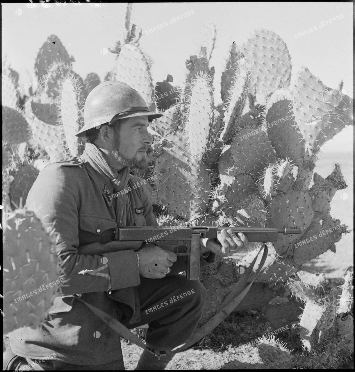 Sergent du 9e RTA (régiment de tirailleurs algériens) de la DMC (Division de marche de Constantine) posté au milieu de cactus et armé d'un pistolet-mitrailleur Thompson M1.