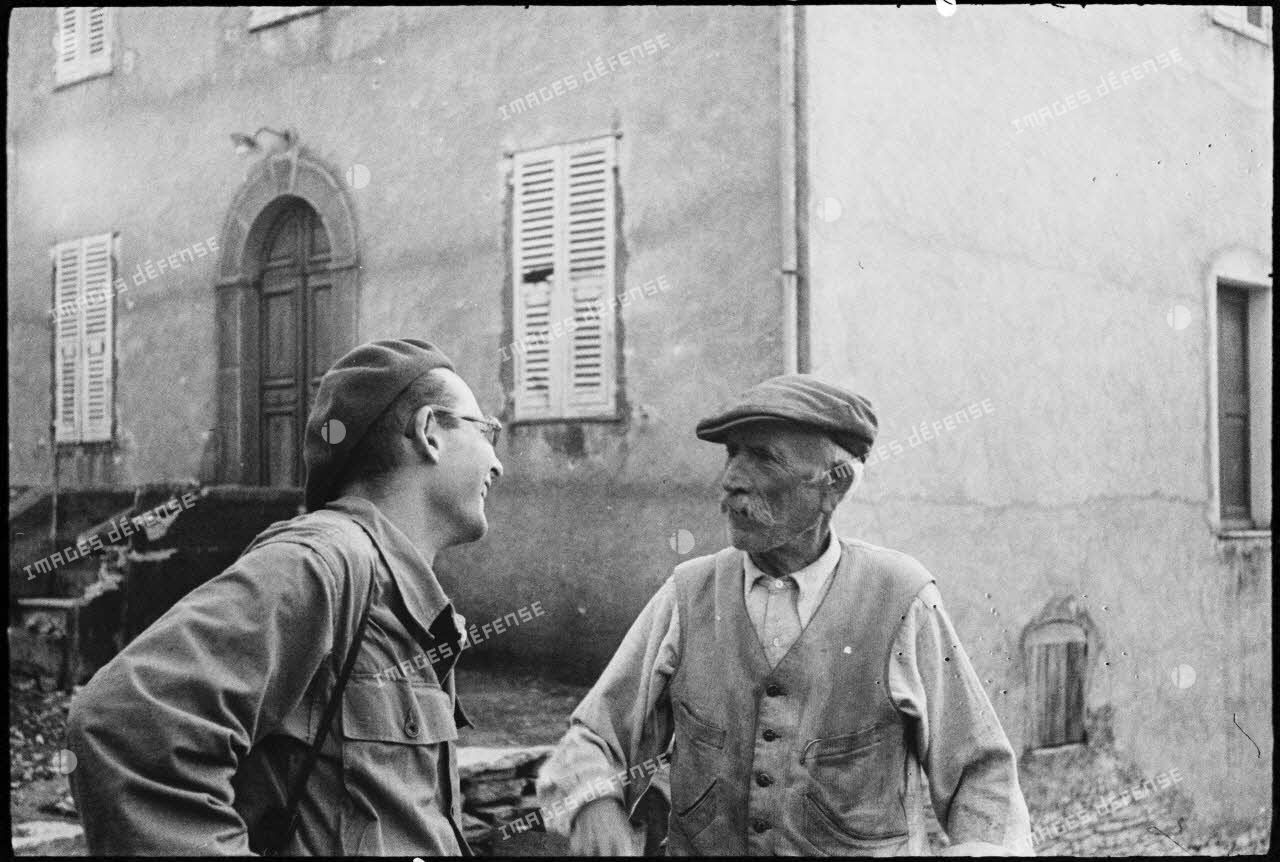 Un habitant du village de Patrimonio libéré discute avec le lieutenant Albert Plécy, officier de presse et photographe du service cinématographique de l'Armée (SCA).
