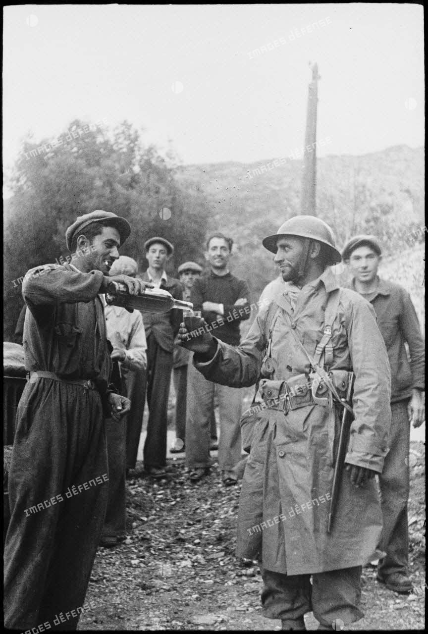 Un habitant du village de Patrimonio libéré offre à boire à un goumier du 2e GTM (groupe de tabors marocains).