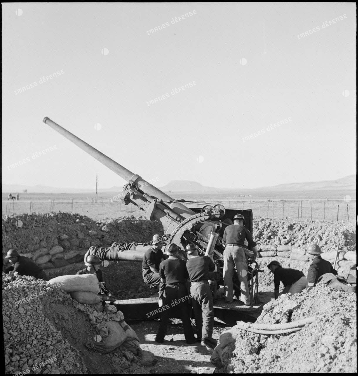 Des canonniers marins, d'une batterie mobile de 90 de marine, approvisionnent un canon de 90 mm, modèle 1939 Schneider antiaérien.