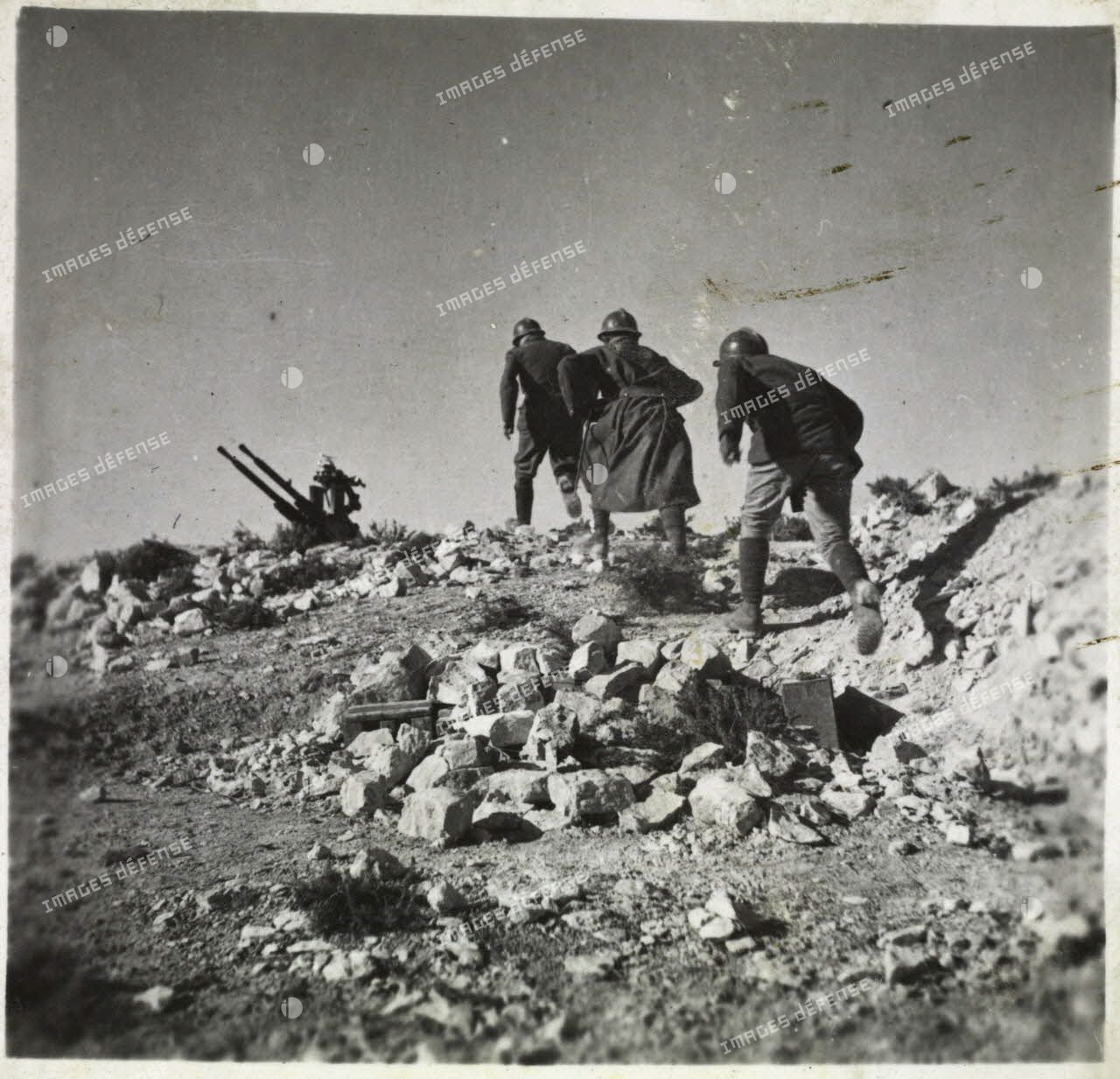 Des artilleurs du 411e RAAA (régiment d'artillerie antiaérienne) courent vers leur mitrailleuse antiaérienne Hochkiss 13,2 mm sur affût bitube.