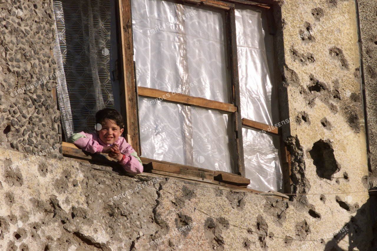 Un enfant afghan à la fenêtre d'un immeuble criblé de balles.