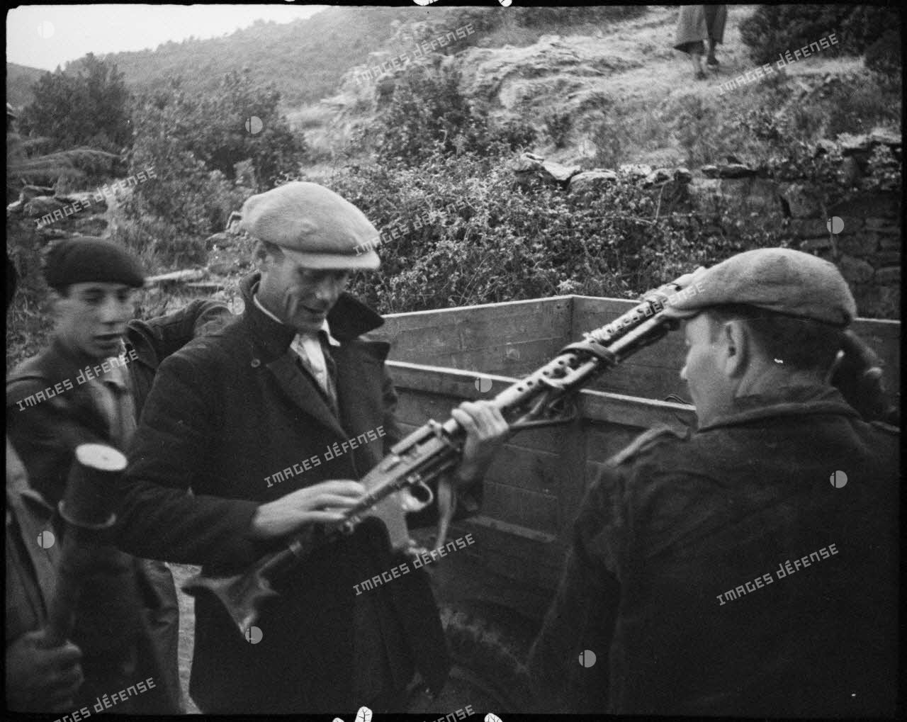 Des partisans corses examinent du matériel abandonné par les Allemands et entreposé dans un camion : des casques, une MG-34 et son chargeur circulaire.