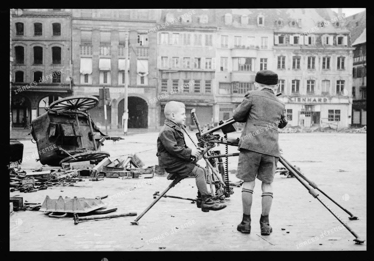 Place Kléber à Strasbourg, des enfants jouent avec une mitrailleuse allemande abandonnée.