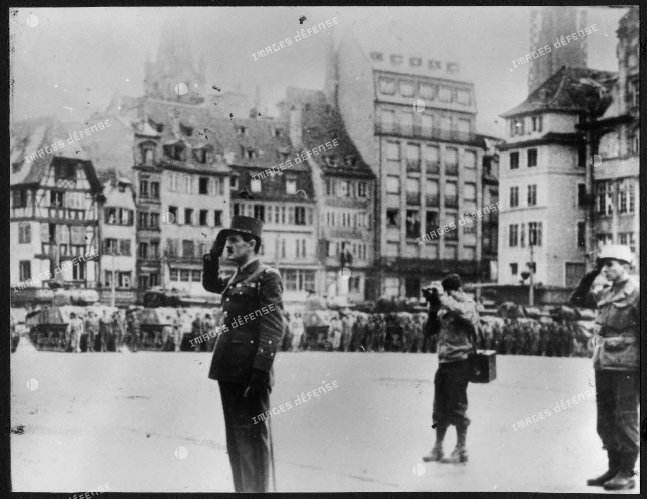 Strasbourg, le 26 novembre 1944, le général Leclerc passe en revue des éléments de la 2e DB (division blindée) place Kléber et salue pendant l'exécution de la Marseillaise.