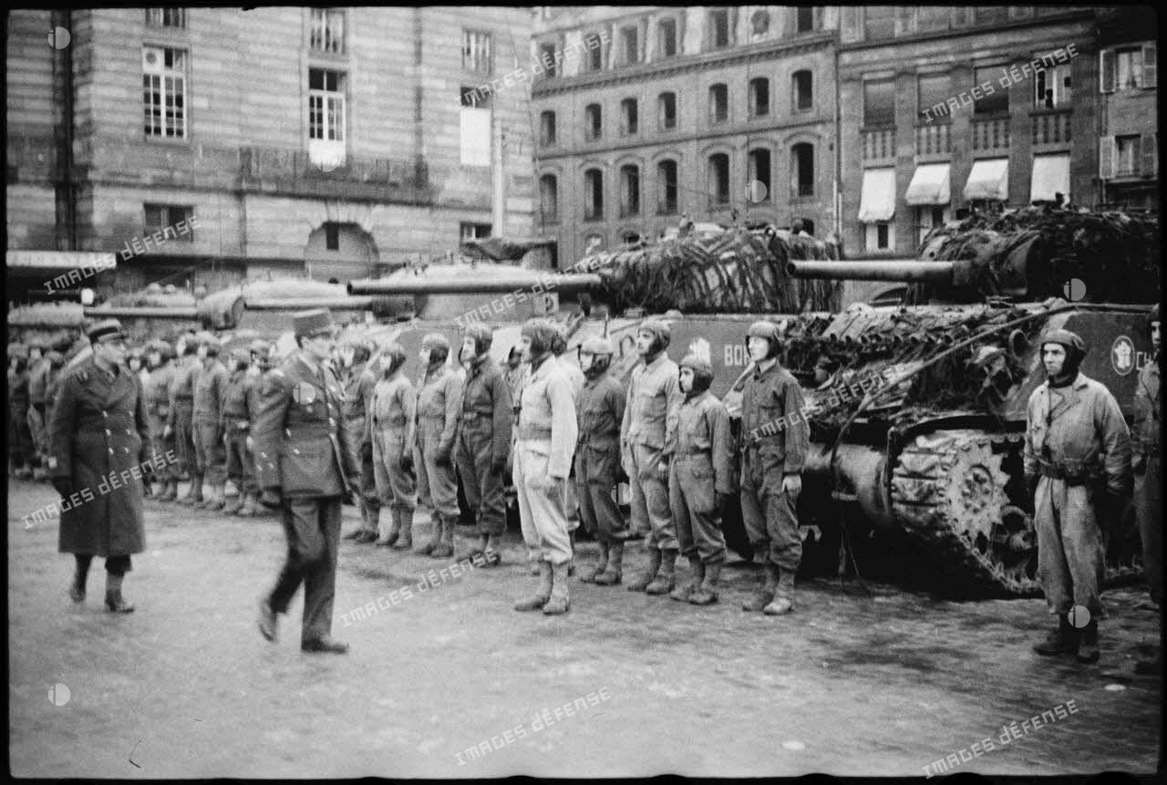 Place Kléber à Strasbourg, lors d'une cérémonie célébrant la libération de la capitale de l'Alsace par la 2e DB (division blindée), le général Leclerc, commandant la 2e DB, suivi du colonel Rouvillois, commandant le 12e régiment de cuirassiers, passe en revue les chars du 4e escadron du 12e RCA (régiment de chasseurs d'Afrique).