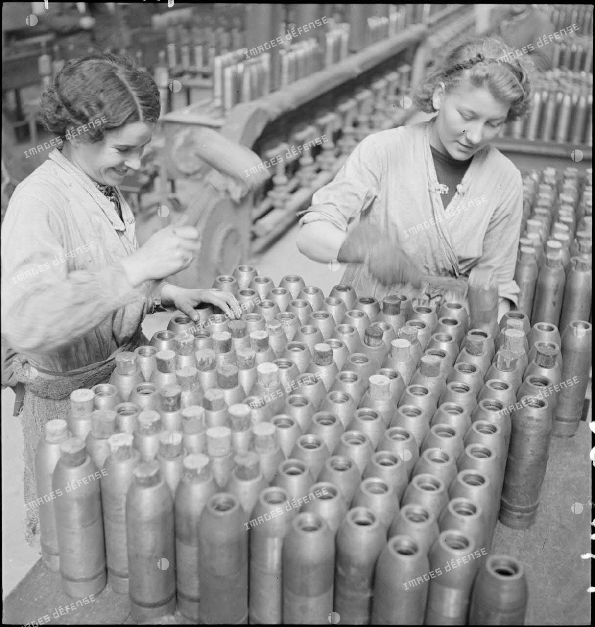 Dans une cartoucherie ou un atelier de fabrication, des ouvrières ferment des enveloppes d'obus de 75 mm avec des bouchons de bois.