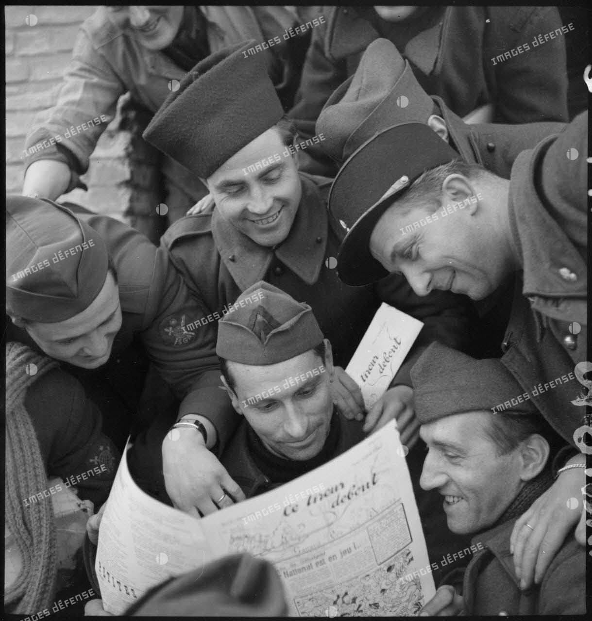 Des soldats de diverses unités (spahis, service géographique des armées...) lisent un numéro du journal de campagne intitulé Le tireur debout.