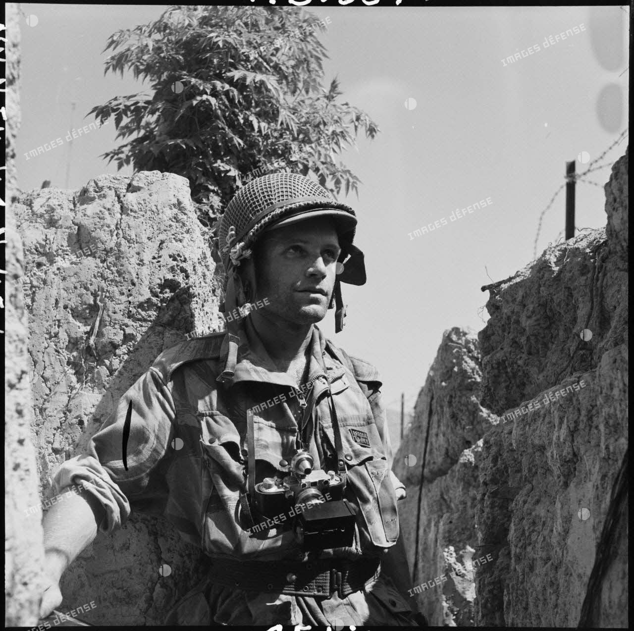 Le photographe du Service presse information (SPI) Jean Péraud, avec son appareil photographique Leica, dans une tranchée d'Isabelle à Diên Bien Phu.