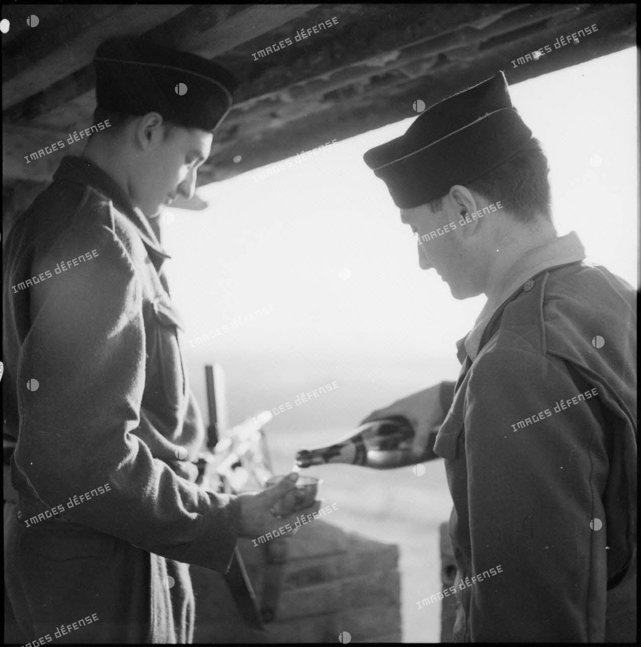 Un soldat sert un verre de champagne à une sentinelle surveillant un poste du delta du Tonkin.