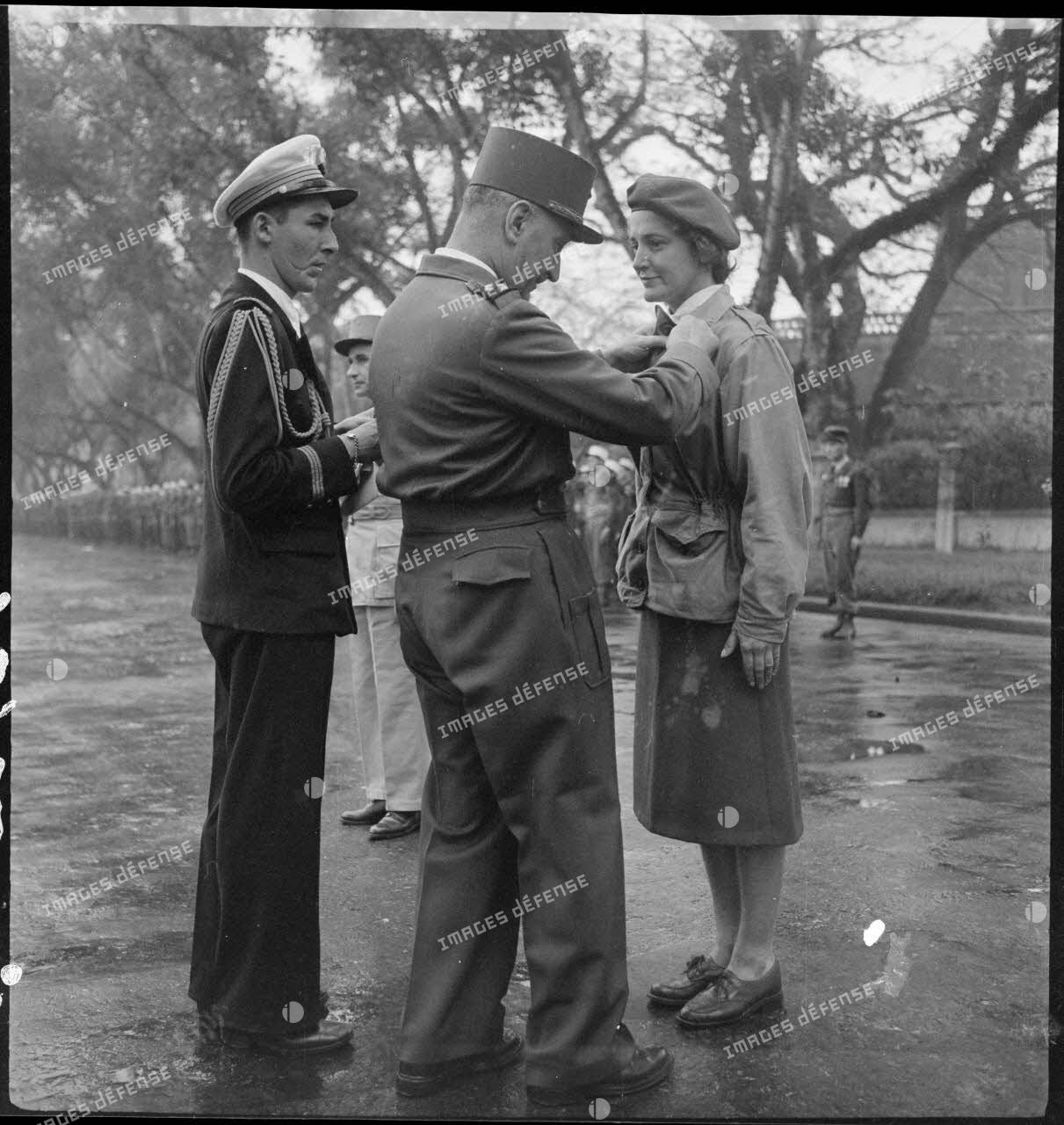 Le général Carpentier, commandant en chef en Indochine, remet la médaille militaire à Geneviève Grall, infirmière du GLAP (Groupement léger aéroporté), au cours d'une prise d'armes à Hanoï.