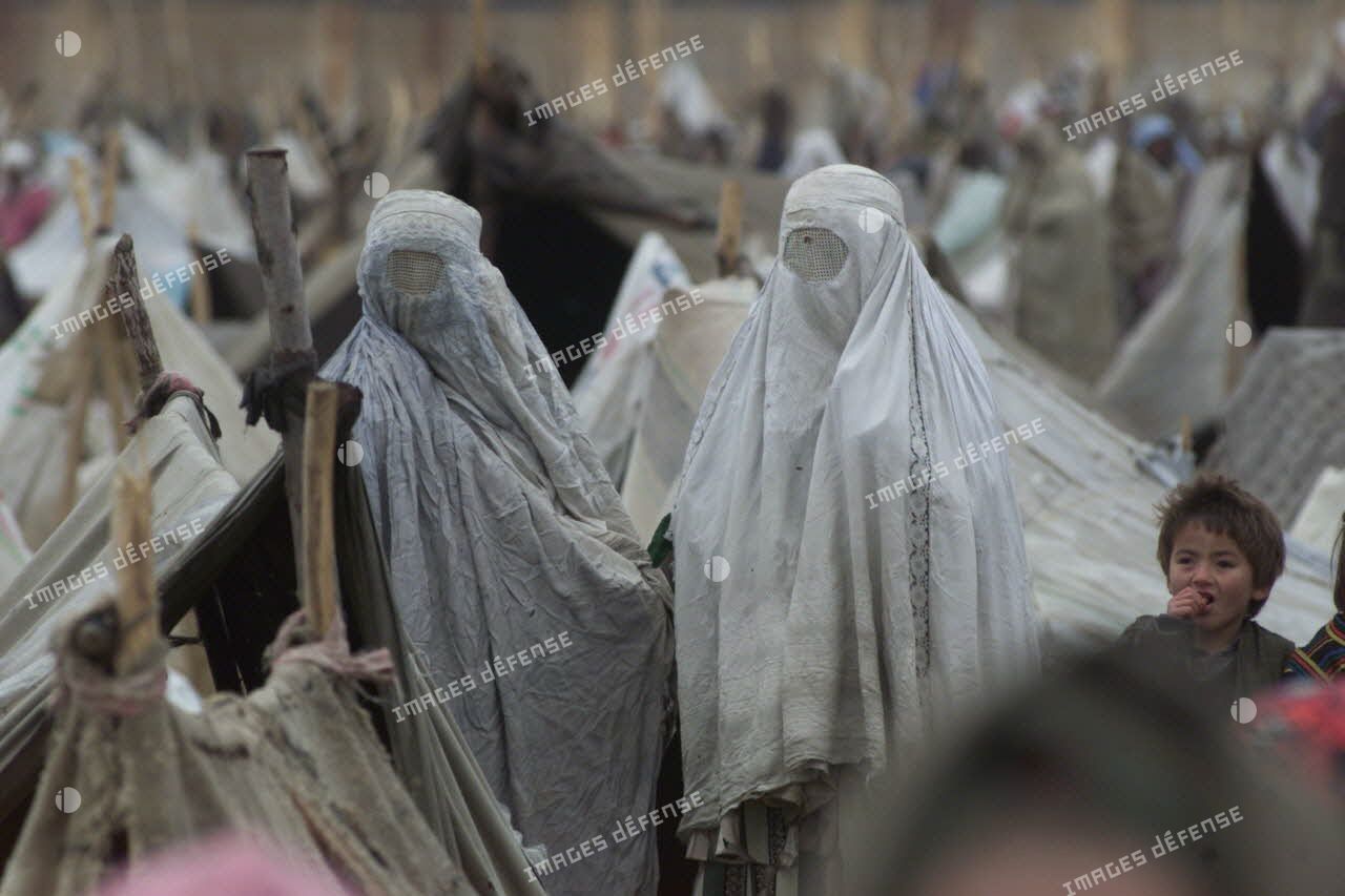 Camp de réfugiés afghans à Mazar e Charif. Portrait de femmes voilées dans le dénuement du camp.