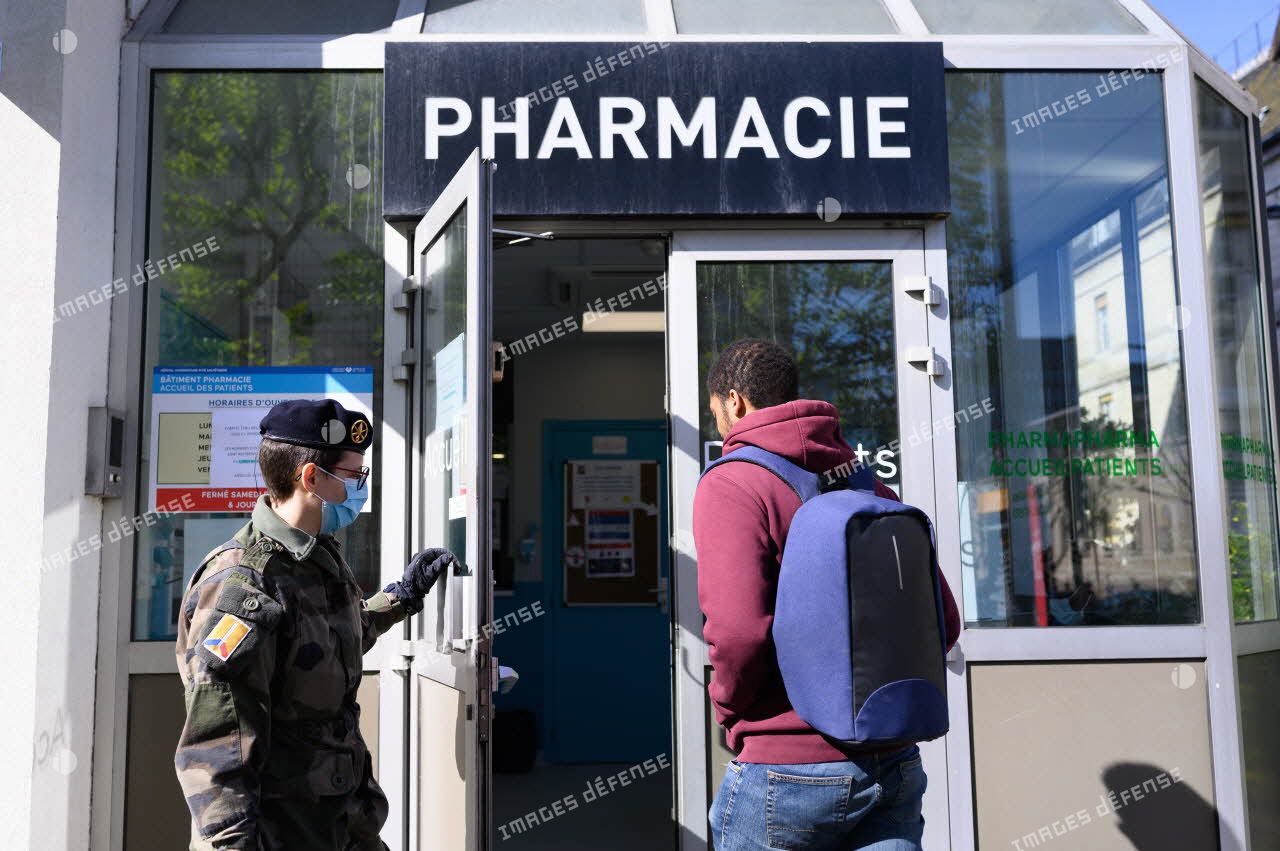 Un soldat du 24e régiment d'infanterie (24e RI) ouvre la porte à un patient à l'entrée de la pharmacie de l'hôpital de la Pitié Salpêtrière à Paris.