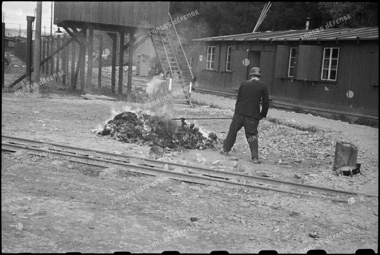 Des pompiers allemands brûlent les vêtements souillés des déportés qui passent à l'épouillage et à qui on fournit des vêtements propres dans le camp de Vaihingen récemment libéré.