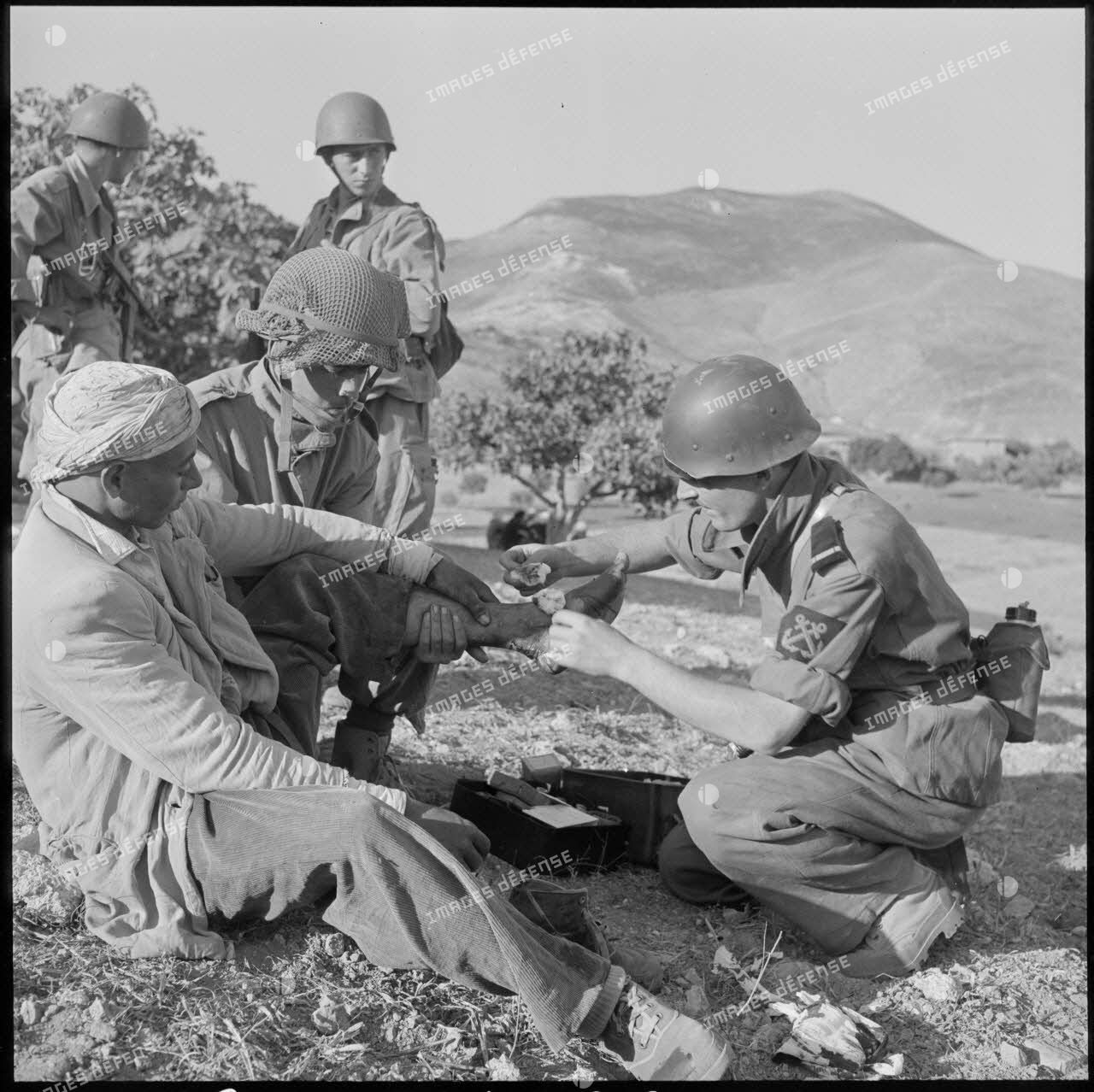 Un aspirant infirmier du 2e bataillon de la 1re demi-brigade de fusiliers-marins (DBFM) soignant un habitant blessé.