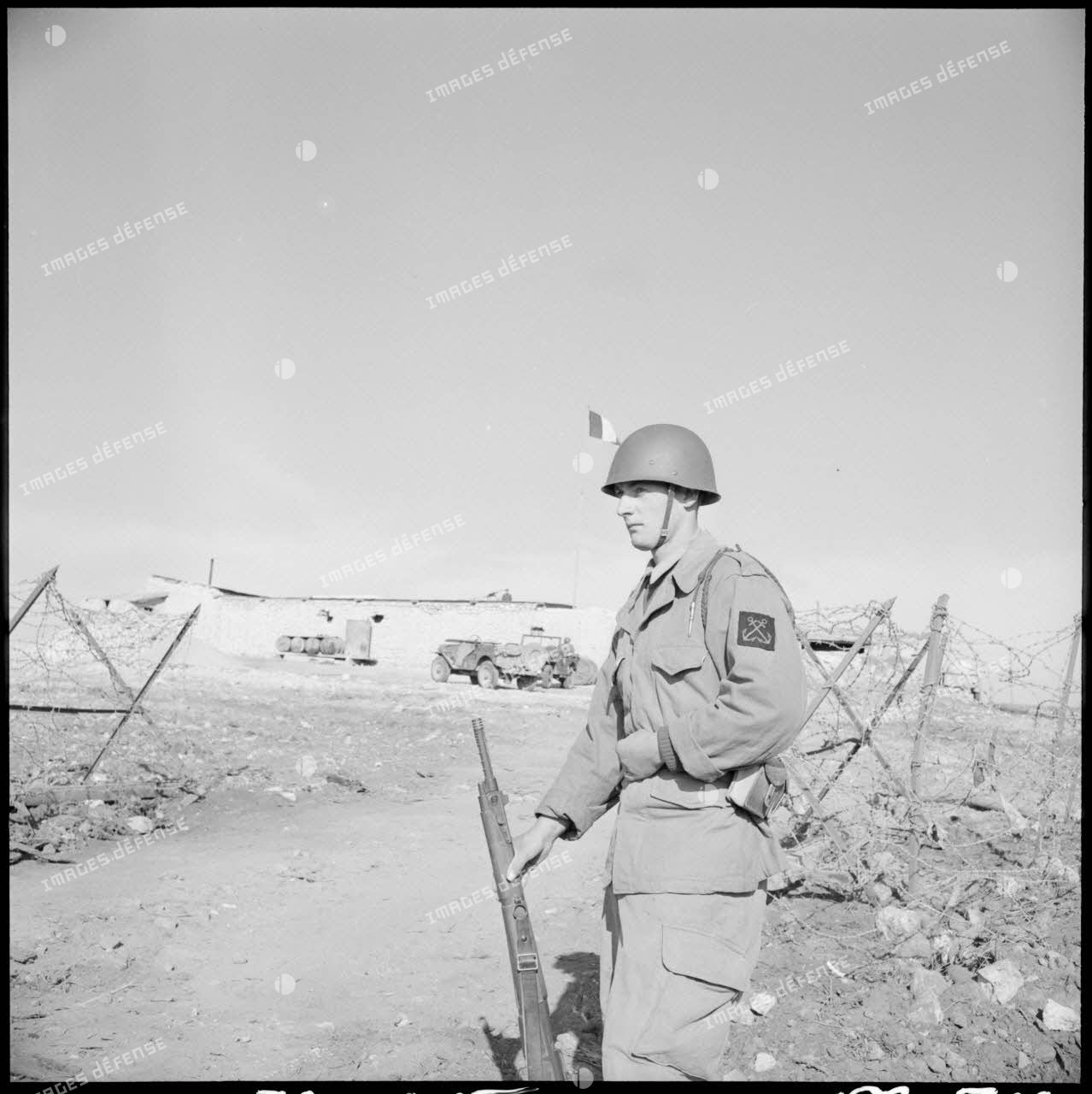 Portrait d'un fusilier-marin montant la garde avec son fusil devant un poste à la frontière algéro-marocaine.