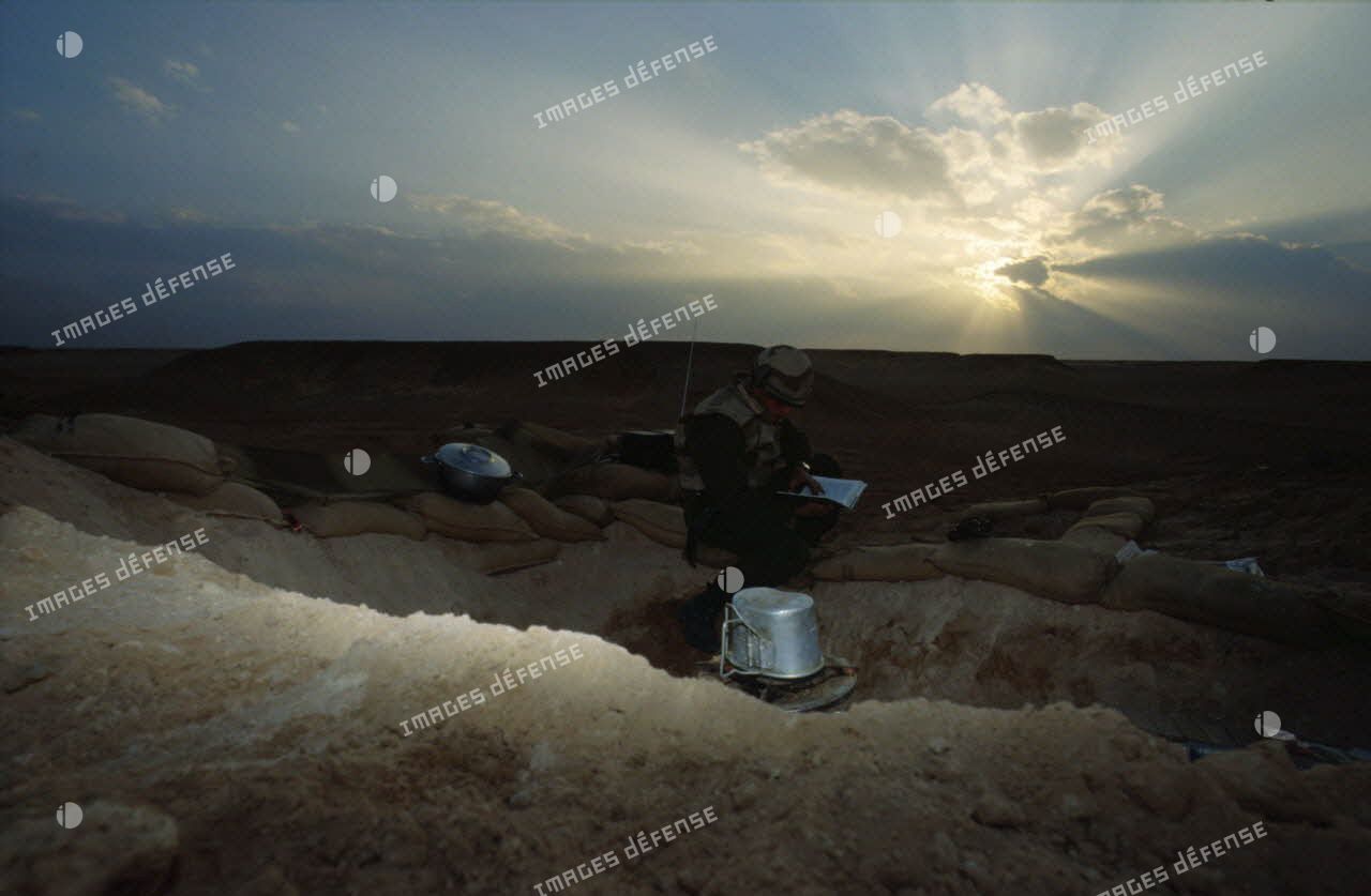 En ZDO (zone de déploiement opérationnel) Olive, trou de combat d'un soldat du 1er RS (régiment de spahis) au repos à l'aube, qui lit ou écoute la radio.
