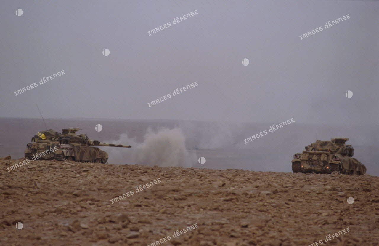 Deux chars lourds de combat AMX-30 B2 du 4e RD (régiment de dragons) progressent au-delà de la frontière irakienne; celui de gauche vient de tirer.