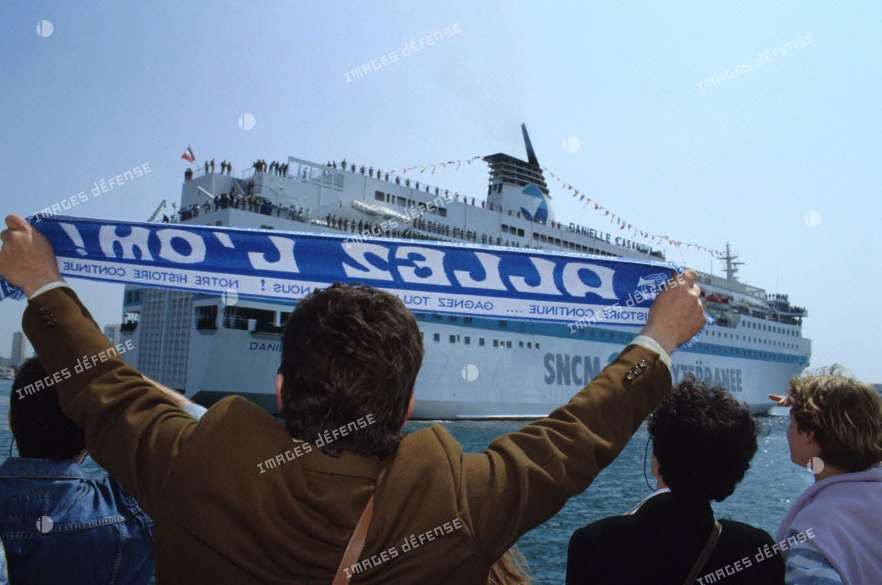 Le ferry affrété Danielle Casanova accoste au port de Toulon sous le regard des familles en attente sur le quai.