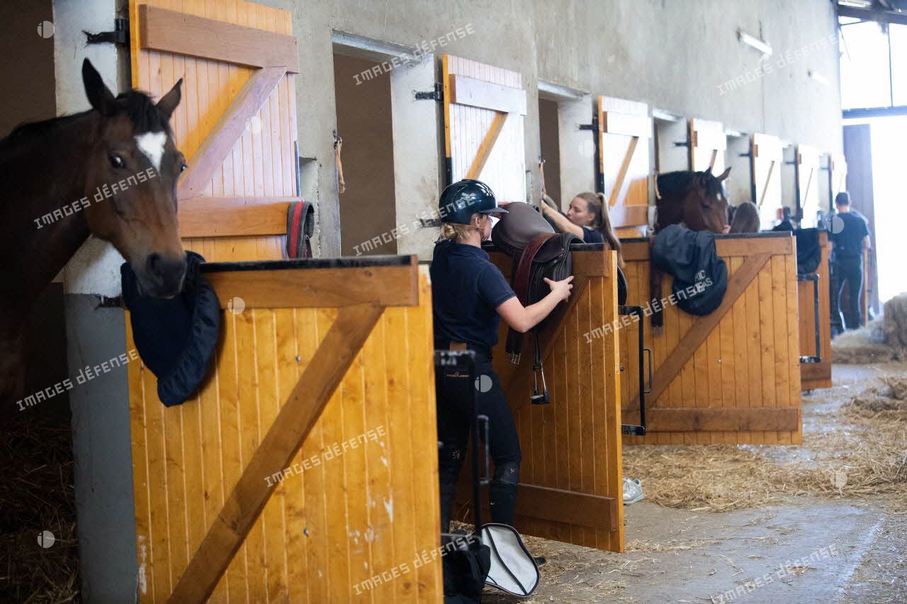 Des élèves s'occupent de leur cheval dans leur box de la section équestre militaire (SEM) pour un cours d'équitation au lycée militaire d'Autun.