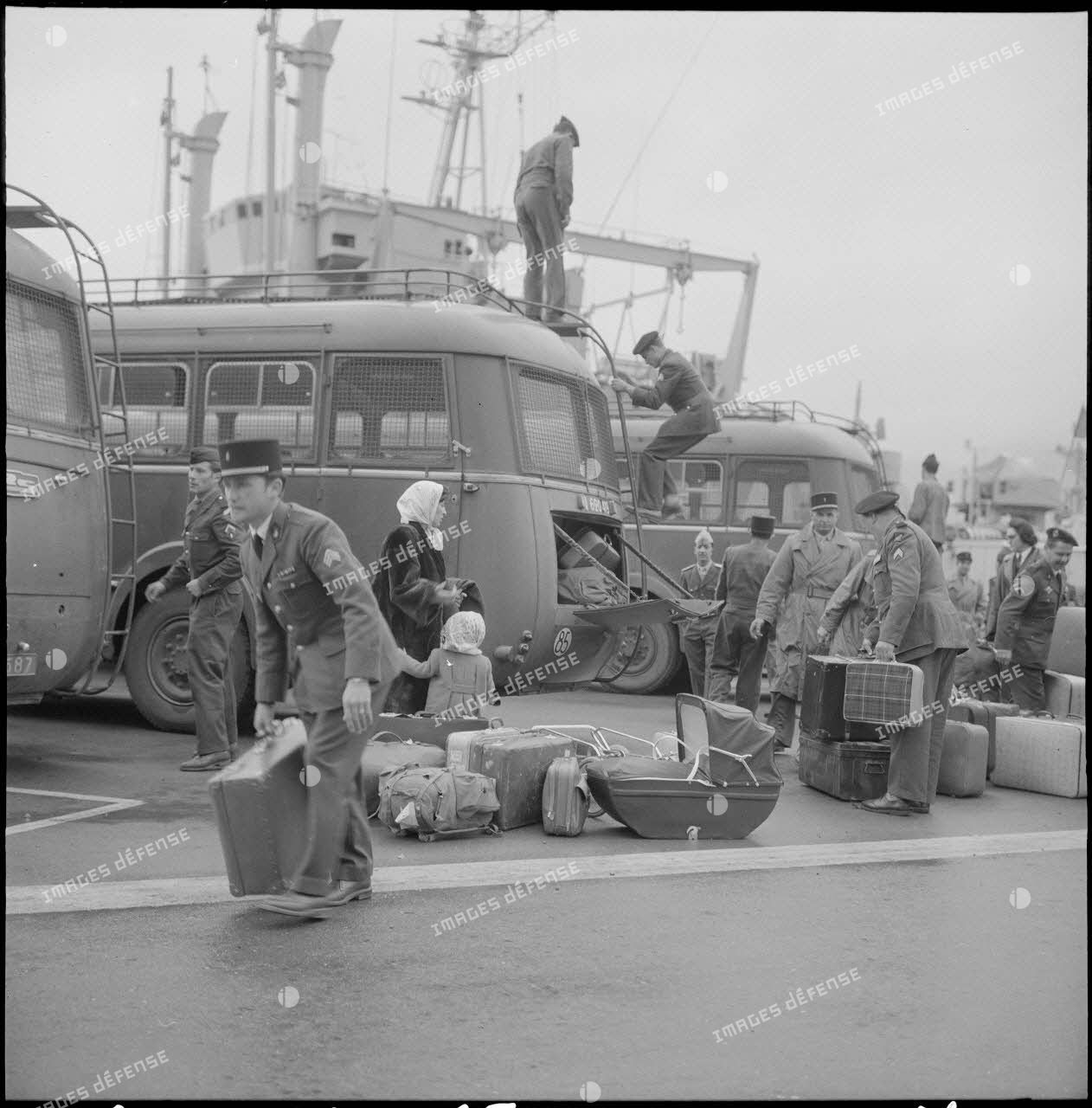 Femmes et enfants partant du port d'Oran pour la France, aidés par des soldats.