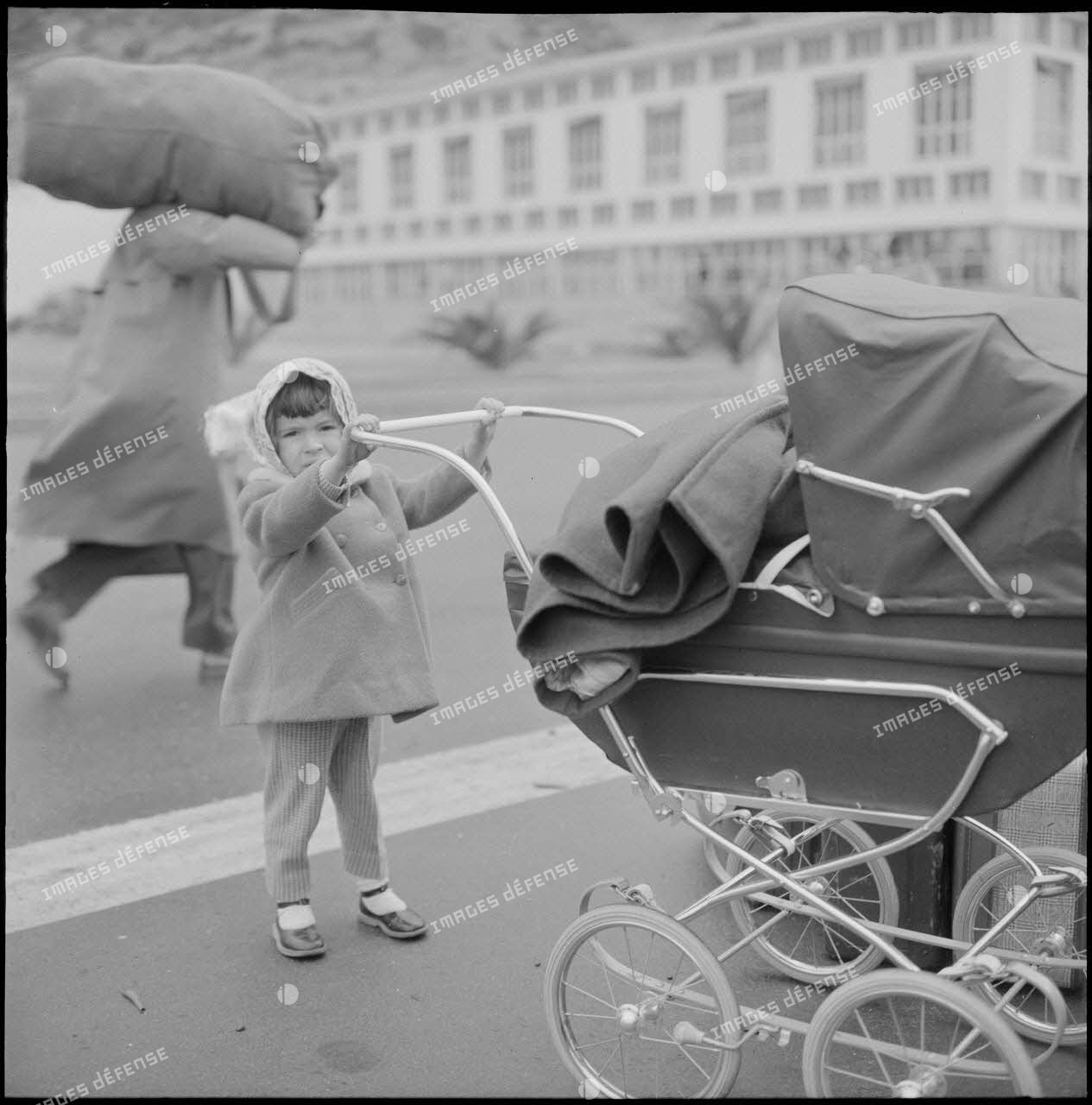 Enfant avec un landeau attendant au port d'Oran le départ pour la France.