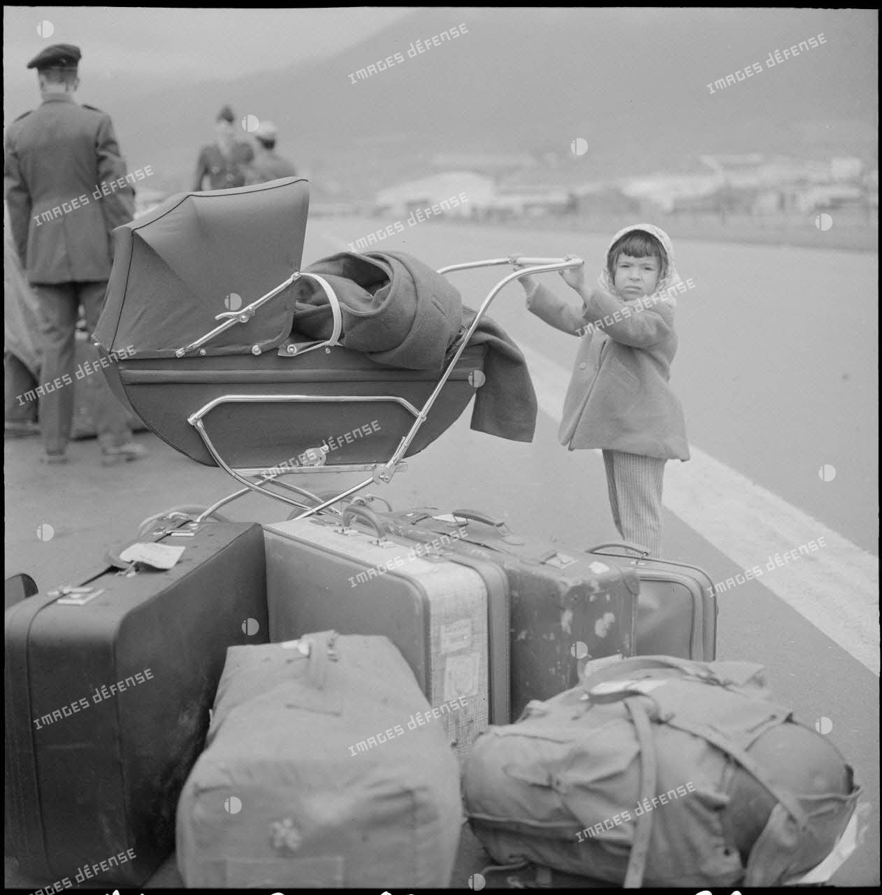 Enfant avec un landeau attendant au port d'Oran le départ pour la France.