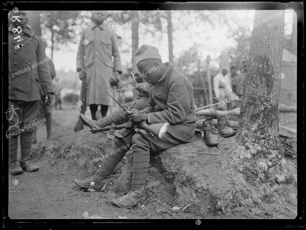 Bois d'Houssoy, près de Remaugis (Somme). Camp de tirailleurs sénégalais, 62e bataillon, Sénégalais nettoyant leurs fusils. [légende d'origine]