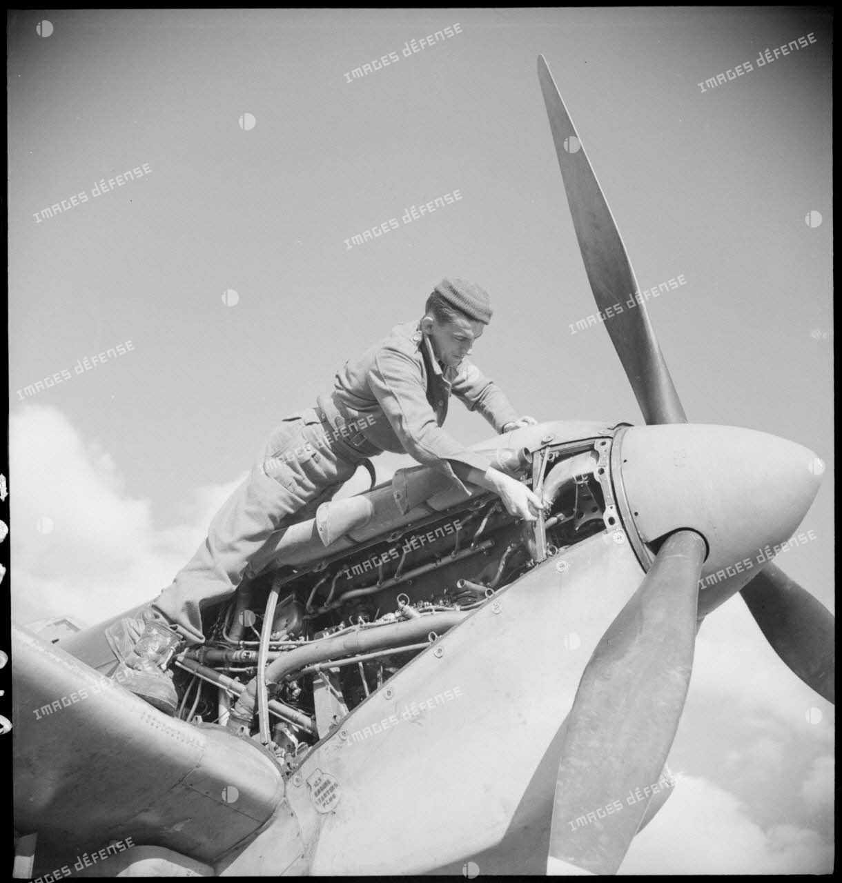 Un mécanicien assure la maintenance du moteur d'un Spitfire Mk V du groupe de chasse (GC) II/7 Nice.