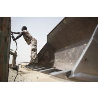 Une sapeur du 19e régiment du génie (RG) arrime un container à une chargeuse pelleteuse 821C pour son transport sur la base de Tombouctou, au Mali.