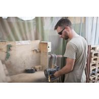 Le sergent-chef Eric du 13e bataillon de chasseurs alpins (BCA) meule une pièce pour la remise en état du système de roulage d'un véhicule de l'avant blindé (VAB) à Tombouctou, au Mali.