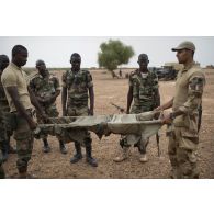 L'auxiliaire sanitaire Iliès encadre des stagiaires nigériens pour la création d'un brancard de fortune à Inatès, au Niger.