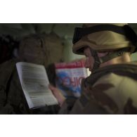 Le médecin des armées Benoît consulte une revue médicale à bord d'un véhicule de l'avant blindé sanitaire (VAB SAN) sur une route de la région de Tillabéri, au Niger.