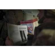 Le médecin des armées Benoît consulte une revue médicale à bord d'un véhicule de l'avant blindé sanitaire (VAB SAN) sur une route de la région de Tillabéri, au Niger.