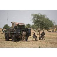 Des sodats du 7e bataillon de chasseurs alpins (BCA) profitent d'une halte pour se restaurer au pied de leur véhicule de l'avant blindé (VAB) lors d'un convoi dans la région de Tillabéri, au Niger.