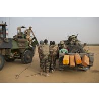 Des soldats nigériens utiliseur le compresseur à air d'un véhicule de l'avant blindé (VAB) pour dépoussiérer leur armement lors de la halte d'un convoi dans la région d'Ayorou, au Niger.