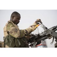 Un soldat nigérien entretient une mitrailleuse lourde Norinco QJC-88 de 12,7 mm à bord d'un pick-up lors de la halte d'un convoi dans la région d'Ayorou, au Niger.