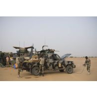 Des soldats nigériens dépoussièrent leur pick-up au moyen d'un compresseur à air lors de la halte d'un convoi dans la région d'Ayorou, au Niger.