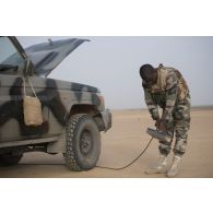 UN soldat nigérien dépoussière son pick-up au moyen d'un compresseur à air lors de la halte d'un convoi dans la région d'Ayorou, au Niger.