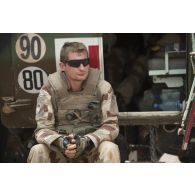 Le médecin des armées Benoît se repose au pied de son véhicule de l'avant blindé sanitaire (VAB SAN) lors de la halte d'un convoi dans la région d'Ayorou, au Niger.