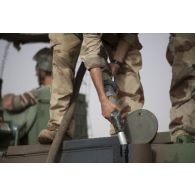 Un soldat du 503e régiment du train (RT) ravitaille un véhicule de l'avant blindé (VAB) en carburant dans le secteur des monts Farach, au Mali.