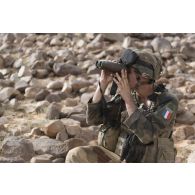 Un soldat du 13e bataillon de chasseurs alpins (BCA) observe le terrain au moyen de jumelles Vector 21 pour le ratissage du mont Mbali, au Mali.