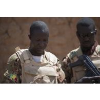 Des soldats maliens fouillent une malle découverte dans un village des monts Farach, au Mali.