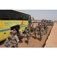Des soldats chargent leurs effets personnels à bord d'un autocar pour leur départ de Niamey, au Niger.