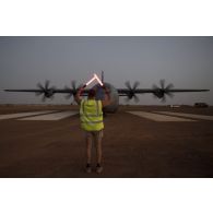 Un soldat du détachement de transit interarmées (DéTIA) guide l'arrivée d'un avion Hercules C-130J-30 de l'US Air Force sur l'aérodrome de Gao, au Mali.