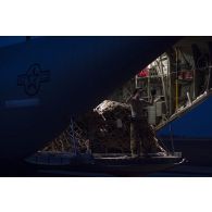 Un aviateur américain guide le déchargement de fret depuis la tranche arrière d'un avion Hercules C-130J-30 de l'US Air Force sur l'aérodrome de Gao, au Mali.