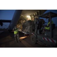 Des soldats du détachement de transit interarmées (DéTIA) déchargent du fret depuis la tranche arrière d'un avion Hercules C-130J-30 de l'US Air Force sur l'aérodrome de Gao, au Mali.