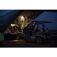 Des soldats du détachement de transit interarmées (DéTIA) déchargent du fret depuis la tranche arrière d'un avion Hercules C-130J-30 de l'US Air Force sur l'aérodrome de Gao, au Mali.