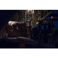 Des soldats du détachement de transit interarmées (DéTIA) déchargent du fret depuis la tranche arrière d'un avion Hercules C-130J-30 de l'US Air Force sur l'aérodrome de Gao, au Mali.